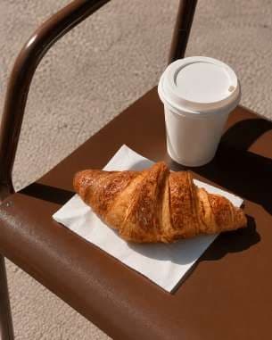 AI render: croissant on a café chair beside a takeaway cup