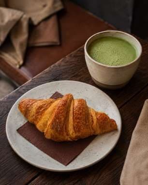 AI render: croissant with a matcha latte on a dark table