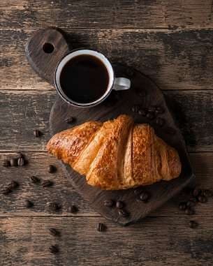 AI render: croissant and black coffee on a board with coffee beans