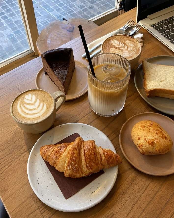 AI render of a croissant with a latte and iced coffee on a window table