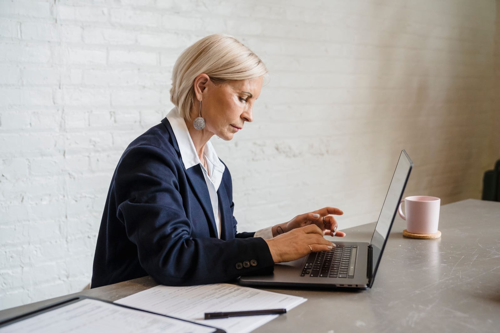 Woman at a desk reviewing a business listing profile on a laptop screen